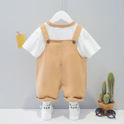 Children's cotton summer cartoon short-sleeved overall in khaki color with white t-shirt and sneakers on hanger.
